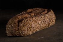 Vista de cerca del pan recién horneado en la mesa oscura - foto de stock