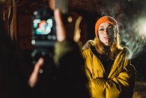 Crop unrecognizable photographer taking shots of stylish woman at night. — Stock Photo