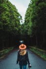 Visão traseira da mulher andando com câmera na estrada na floresta — Fotografia de Stock