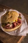 Délicieux sandwich au pastrami avec cornichons et moutarde enveloppé dans du papier — Photo de stock