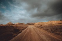 Пряма дорога в пустельному пейзажі під жорстким хмарним пейзажем — стокове фото