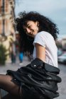 Cheerful curly woman posing in city — Stock Photo