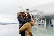 Happy young man embracing and holding in mid air girlfriend at port. — Stock Photo