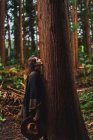 Жінка спирається на дерево в лісі — стокове фото