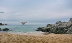 Чотириногий безпілотник в повітрі на піщаному пляжі — стокове фото