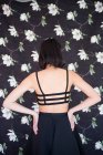 Visão traseira da mulher em sutiã preto sobre o pano de fundo floral — Fotografia de Stock