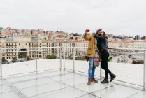 Sorridente coppia prendendo selfie contro paesaggio urbano — Foto stock