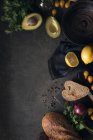 Dall'alto ciotola vuota e avocado con limone e pane su sfondo scuro . — Foto stock