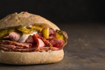 Crop pastrami sandwich with pickles and mustard — Stock Photo