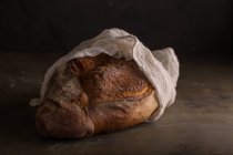 Pão recém-assado coberto com toalha no fundo escuro — Fotografia de Stock