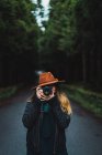 Woman taking shot with camera at road in woods — Stock Photo
