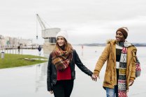 Young couple holding hands and walking in harbor — Stock Photo