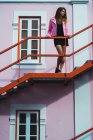 Молодая женщина в розовой куртке позирует на лестнице на улице — стоковое фото