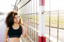 Junge Frau posiert am Gitter und schaut zur Seite — Stockfoto