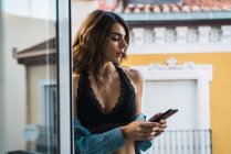 Молода жінка використовує смартфон на балконі — стокове фото