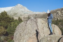Vue latérale de la femme avec smartphone sur le rocher à la nature — Photo de stock