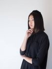 Femme élégante en noir posant avec le menton à portée de main en studio — Photo de stock