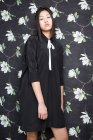 Hübsche asiatische Frau im schwarzen Kleid auf floralem Hintergrund — Stockfoto