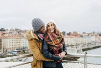 Cheerful young man embracing girl on background of city. — Stock Photo