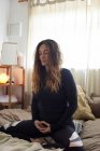 Женщина делает упражнения йоги на кровати дома — стоковое фото