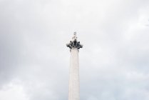 Desde abajo vista del monumento arquitectónico de columna blanca con estatua contra cielo nublado
. - foto de stock