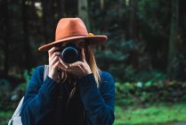Femme en chapeau prendre des photos dans la forêt — Photo de stock