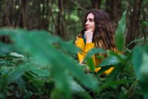 Молодая женщина сидит в зеленом лесу и смотрит в сторону . — стоковое фото