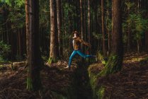 Щаслива молода жінка стрибає через дренаж в лісі — стокове фото