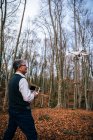 Uomo che vola drone con telecomando nella foresta — Foto stock