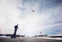 Uomo drone volante con telecomando nel paese invernale — Foto stock