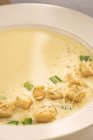Piatto con gustosa zuppa cremosa servita con crostini e lattuga . — Foto stock