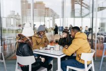 Amigos alegres sentados no café e bebendo café — Fotografia de Stock