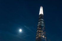 Low angle view of illuminated modern skyscraper facade over night sky — Stock Photo