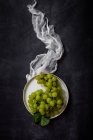 Natura morta di chicchi d'uva freschi su piatto a tavolo scuro . — Foto stock