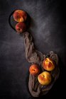 Stillleben von reifen Pfirsichen auf Stoff am dunklen Tisch. — Stockfoto