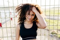 Young woman posing at grid and holding curly hair — Stock Photo