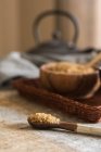 Закрыть вид ложки за миской с коричневым сахаром на плетеном лотке — стоковое фото