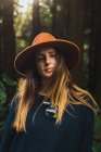 Portrait of young woman in hat at sunny forest — Stock Photo