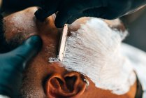 Barber's hand shaving beard of customer — Stock Photo