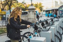 Mujer alegre tomando bicicleta en el parque - foto de stock