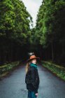 Вид збоку жінки в капелюсі позує на лісовій дорозі — стокове фото