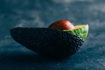 Halbierte Avocado auf dunklem Hintergrund — Stockfoto