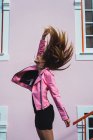 Side view of happy woman with flying hair jumping on city street. — Stock Photo