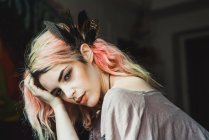 Привлекательная женщина с розовыми волосами и перьями, смотрящая в камеру — стоковое фото