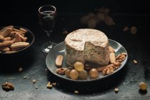 Natura morta di formaggio azzurro con chicchi d'uva e noci su superficie scura — Foto stock