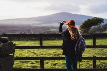 Rear view of woman leaning at rural fence on field — Stock Photo