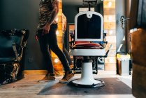 Crop uomo posa vicino sedia barbiere — Foto stock