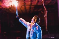 Молодая женщина позирует с пылающим факелом в заброшенном здании — стоковое фото