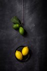 Bodegón de limones frescos y limas sobre mesa oscura . - foto de stock