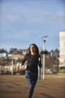 Mujer con auriculares corriendo en la escena urbana - foto de stock
